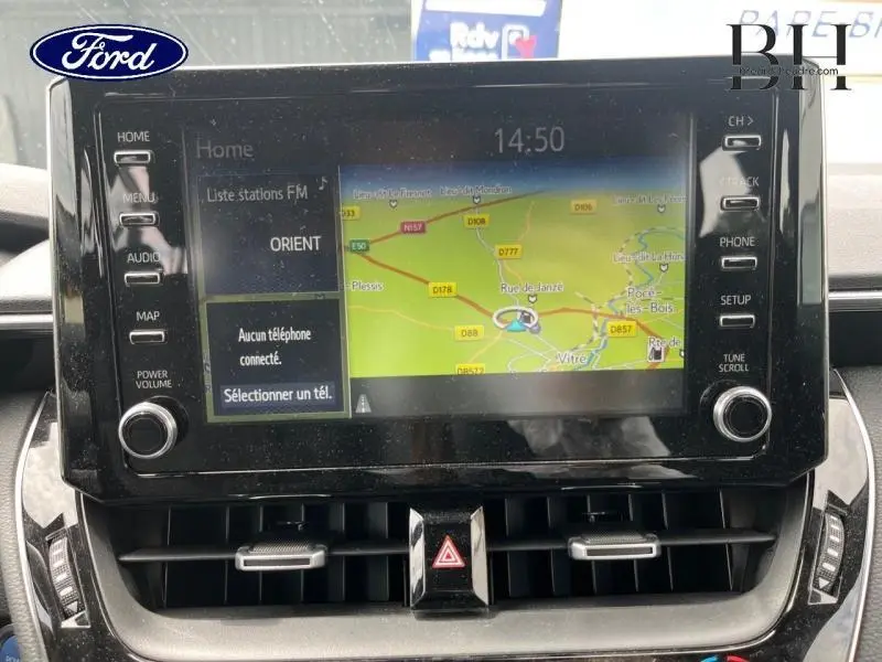 Écran tactile central avec GPS affichant une carte, entouré de commandes sur une Toyota Corolla blanche.