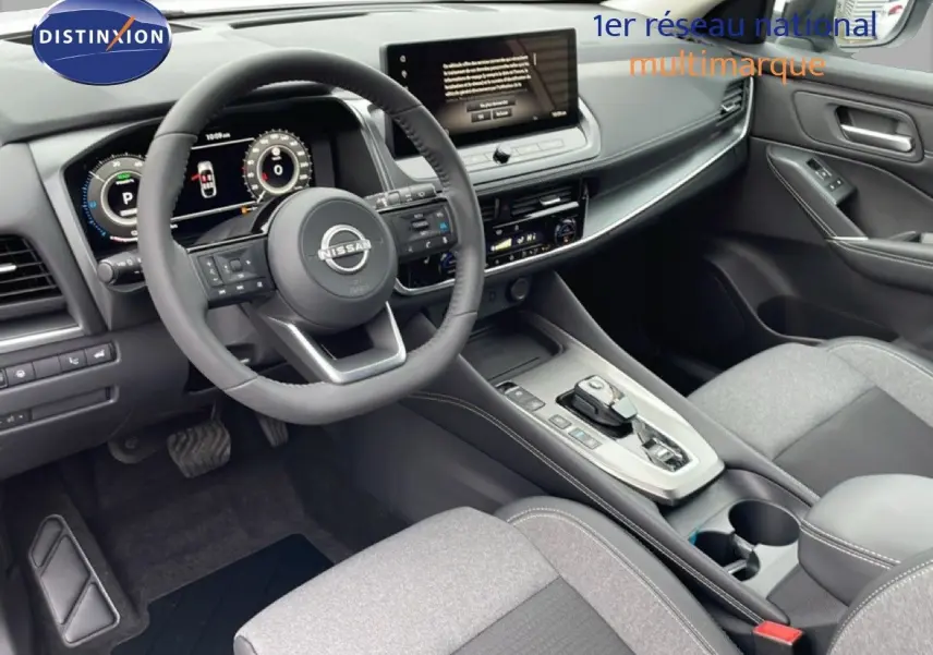 Vue intérieure avant du Nissan Qashqai 1.5 E-POWER 2025, tableau de bord et volant noirs avec écran central tactile.