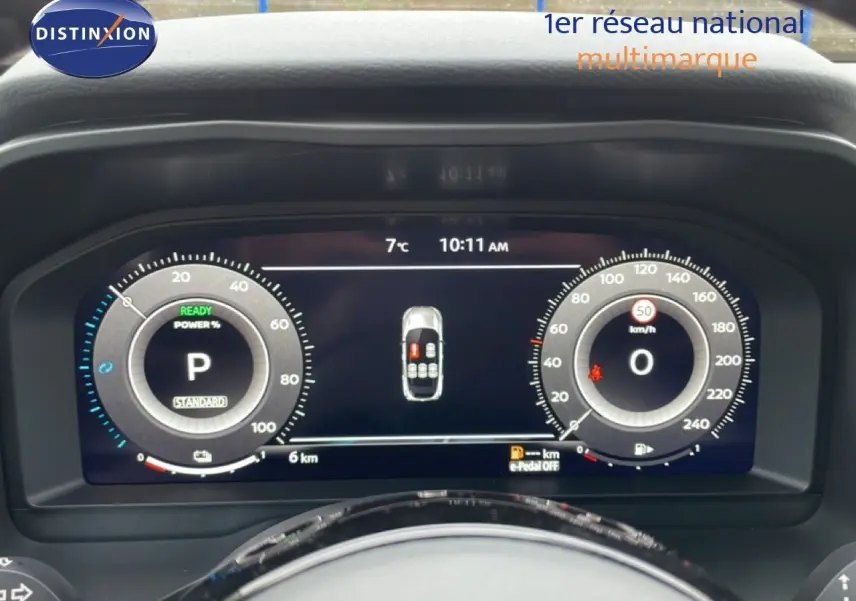 Tableau de bord numérique du Nissan Qashqai blanc nacré, affichage vitesse et état véhicule à 10h11, vue frontale rapprochée.