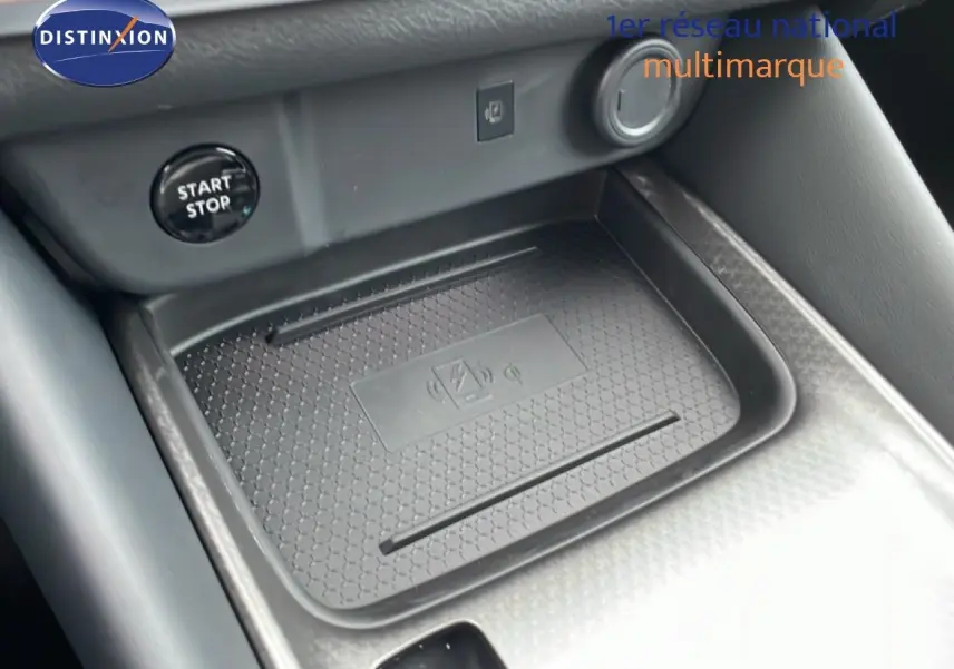 Gros plan sur la console centrale du Nissan Qashqai 2025, avec zone de charge sans fil et bouton start/stop visible.