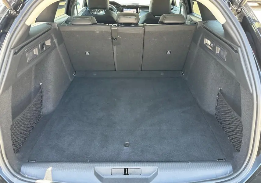 Coffre spacieux ouvert de la Peugeot 308 SW Hybrid 145 noir, avec sièges arrière en position relevée et filet de rangement latéral.