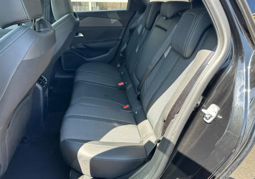 Vue intérieure côté arrière droit du Peugeot 308 SW Hybrid noir, montrant les sièges arrière en tissu et cuir avec ceinture de sécurité.