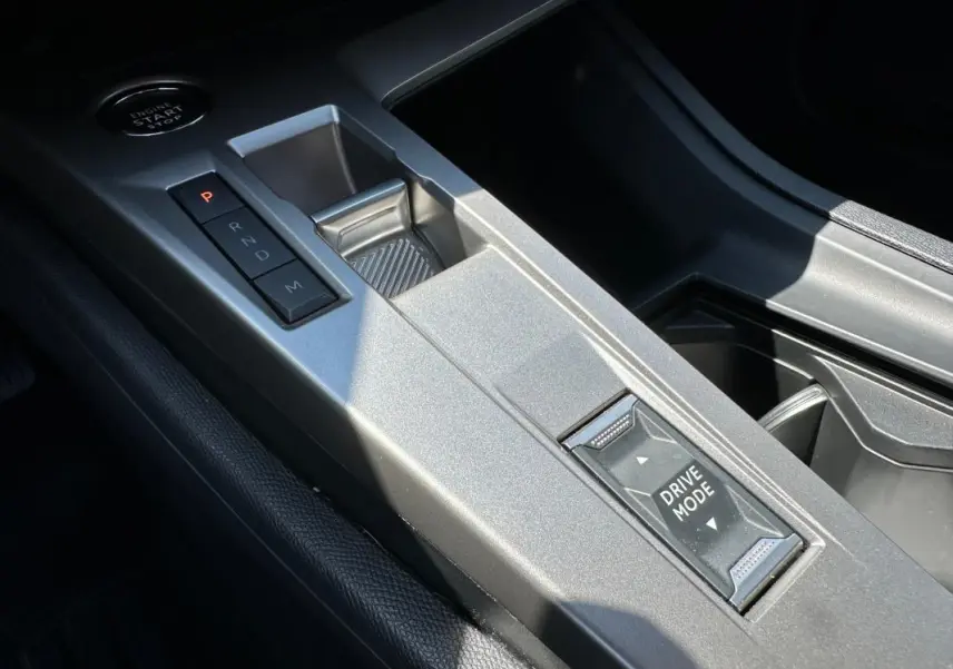 Gros plan sur la console centrale grise avec sélecteur de boîte auto et bouton Drive Mode du Peugeot 308 SW Hybrid 2025.