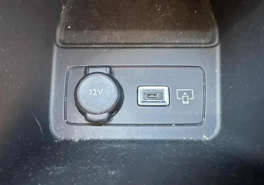 Gros plan sur la prise 12V et port USB-C dans l'habitacle noir du Peugeot 308 SW Hybrid 2025.