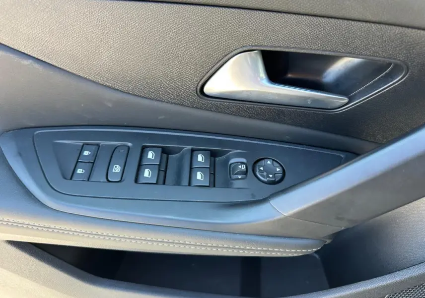 Détail de la porte côté conducteur de la Peugeot 308 SW Hybrid noire, montrant les commandes des vitres et rétroviseurs.