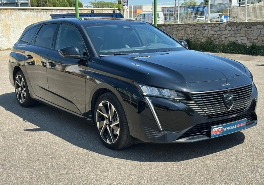 Peugeot 308 SW Hybrid noir vue 3/4 avant droit, avec jantes alliage 17 pouces et calandre distinctive.