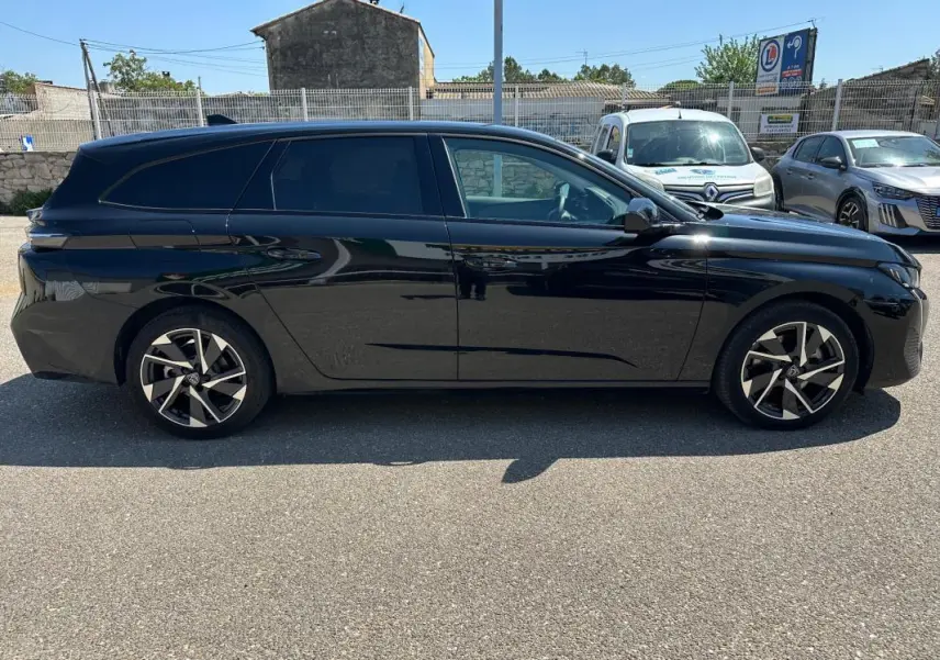 Peugeot 308 SW Hybrid noir vue de profil côté gauche, avec jantes alliage 17 pouces et vitres teintées.