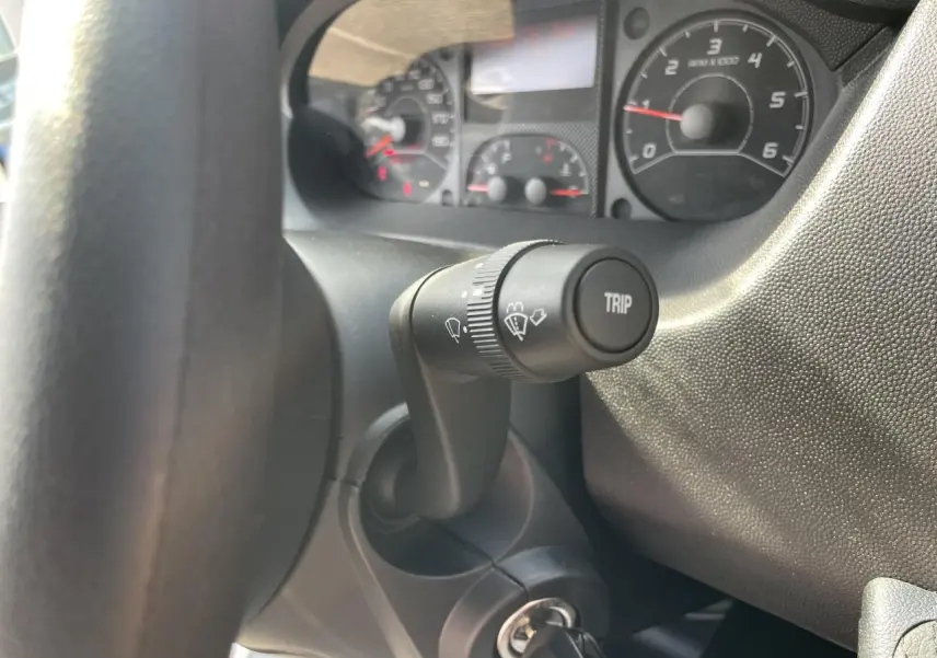 Gros plan sur la manette de commande d’essuie-glace et le tableau de bord noir du Peugeot Boxer Fourgon blanc, côté conducteur.