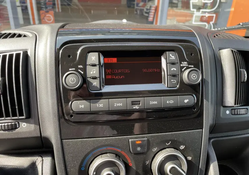 Tableau de bord du Peugeot Boxer Fourgon 2023 avec radio numérique et commandes de climatisation visibles en gros plan.
