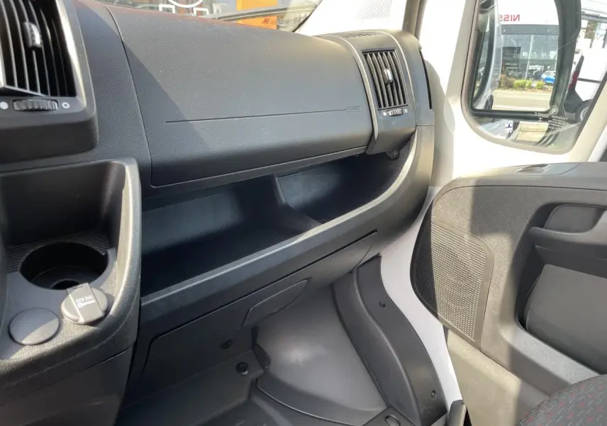 Intérieur côté passager du Peugeot Boxer Fourgon blanc 2023, tableau de bord et porte avec rangement visible.