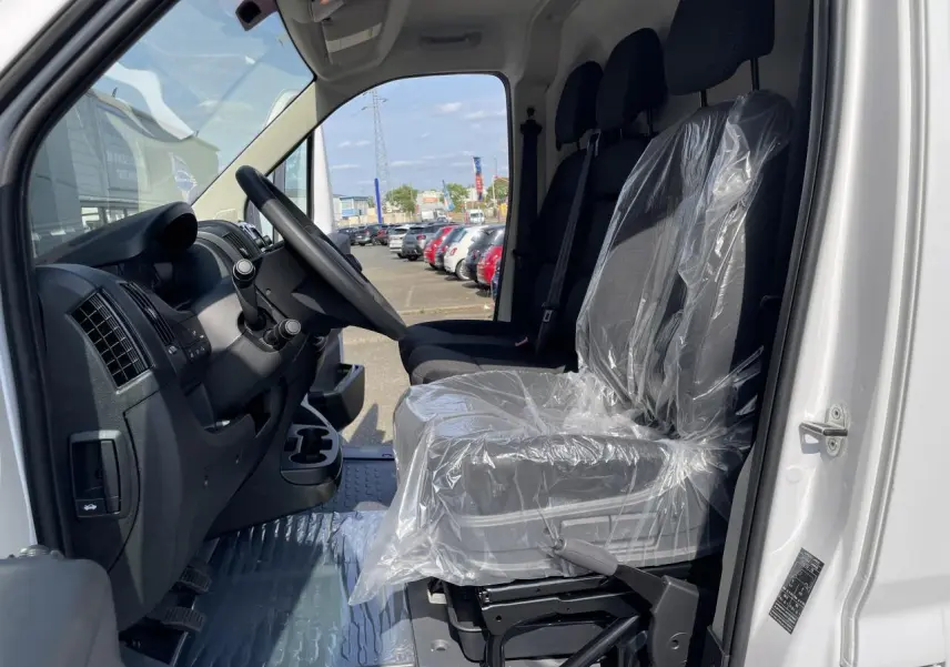 Vue intérieure côté conducteur du Peugeot Boxer Fourgon blanc 2023, siège protégé par housse plastique.