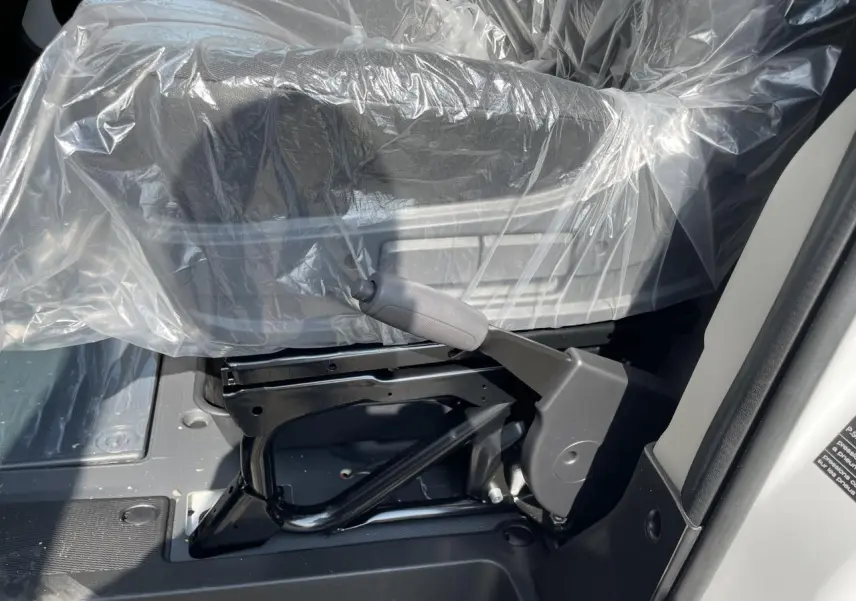 Détail du levier de frein à main côté droit sous le siège conducteur protégé par une housse plastique dans un Peugeot Boxer blanc.