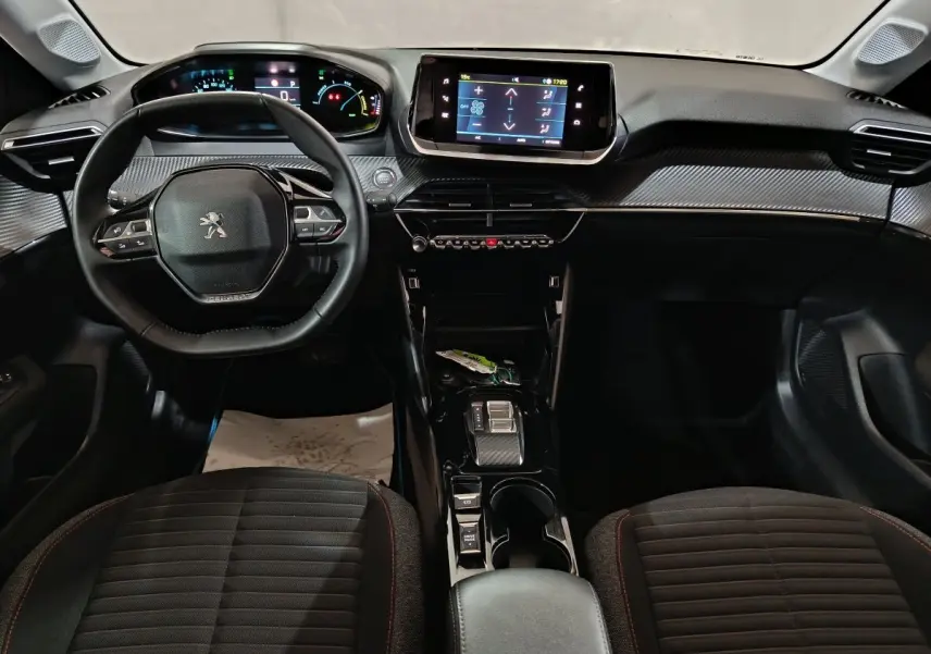 Intérieur du Peugeot 208 électrique 2023 vu de face, tableau de bord moderne avec écran tactile et volant cuir multifonctions.