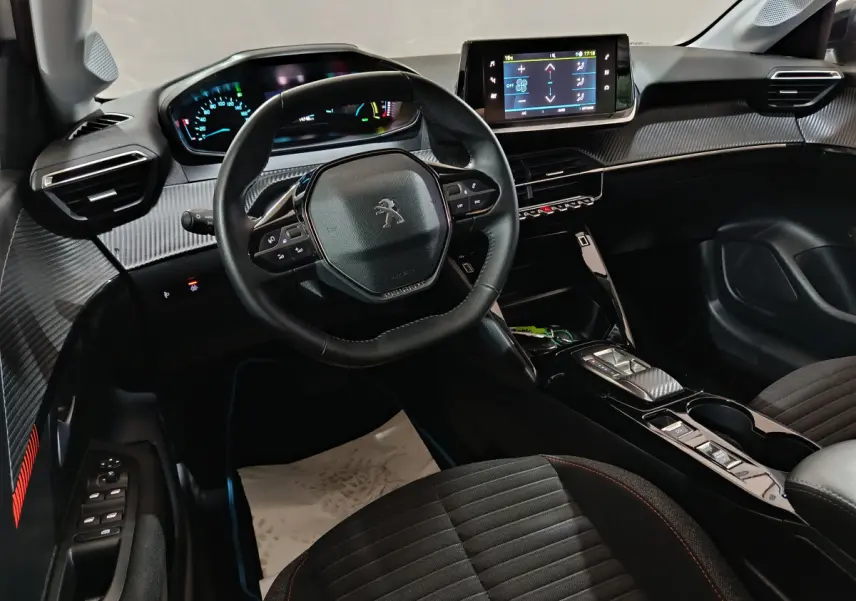 Intérieur de la Peugeot 208 électrique 2023 vu côté conducteur, tableau de bord moderne avec écran tactile central.