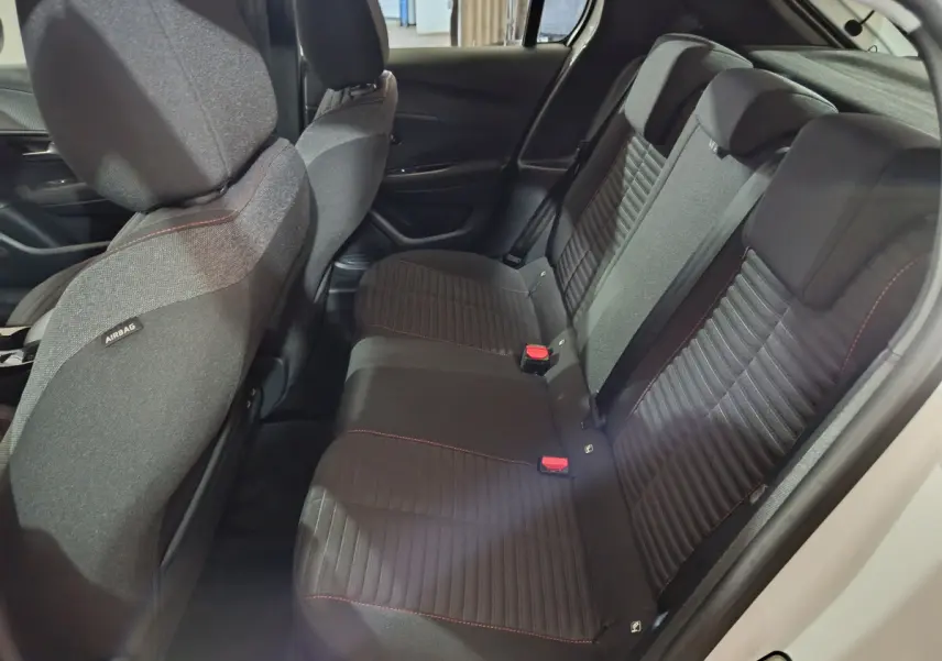 Banquette arrière noire avec surpiqûres rouges vue côté droit dans une Peugeot 208 électrique blanche 2023.