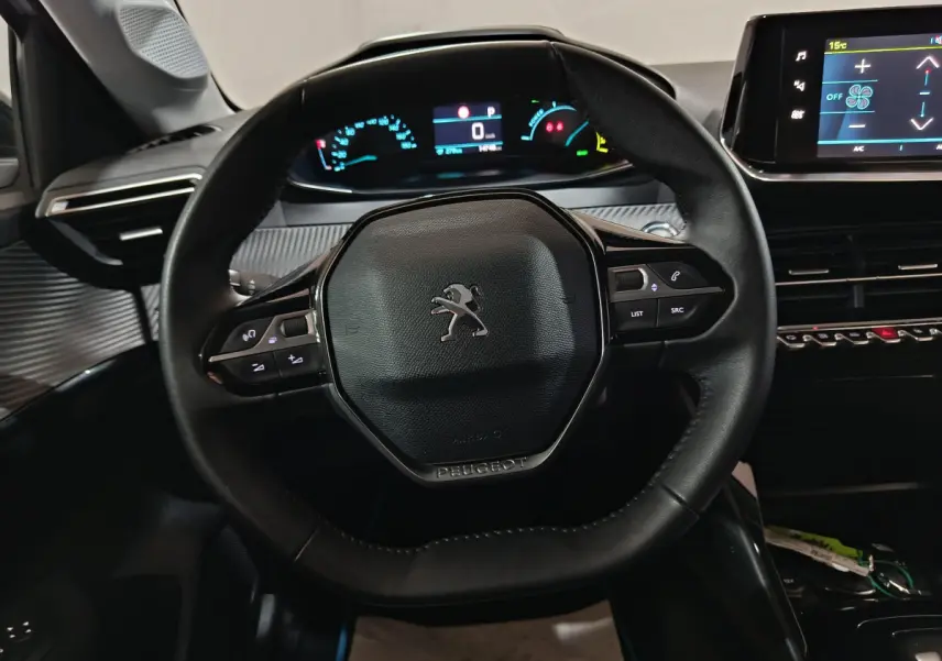 Vue rapprochée du volant cuir noir et du tableau de bord digital de la Peugeot 208 électrique 2023, intérieur moderne.