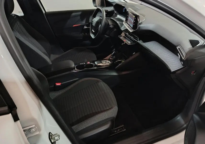 Intérieur de la Peugeot 208 électrique blanc, vue côté conducteur, tableau de bord moderne avec écran tactile central.