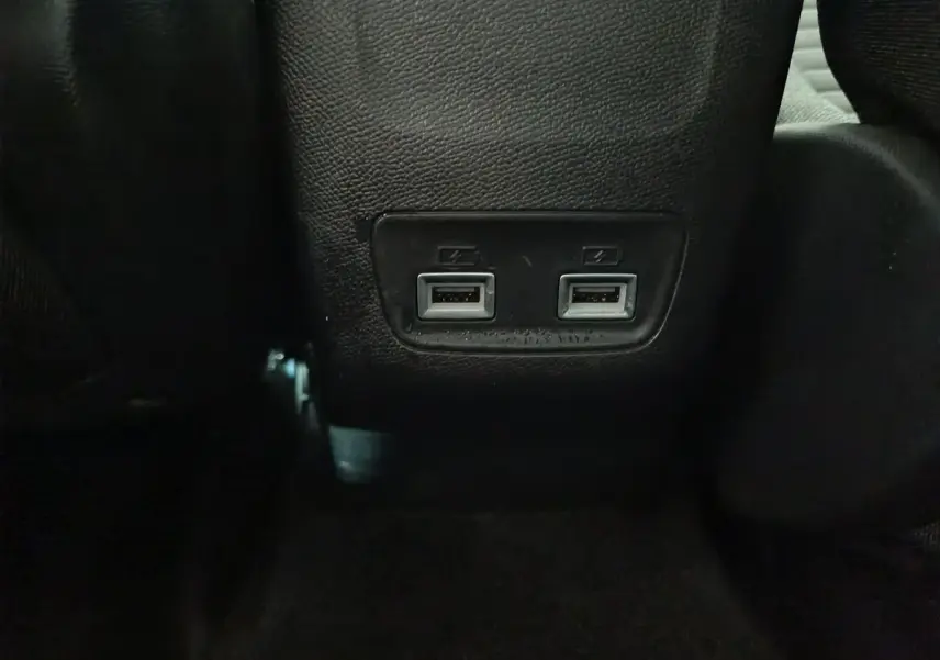Prise double USB arrière sur console centrale noire dans l'habitacle de la Peugeot 208 électrique blanche 2023.