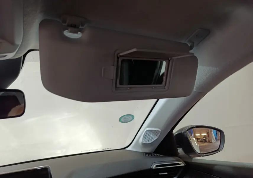 Intérieur du Peugeot 208 électrique blanc 2023, vue côté passager avec pare-soleil et miroir de courtoisie ouvert.
