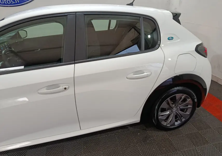 Profil côté droit d'une Peugeot 208 électrique blanche 2023 avec logo "e" bleu sur l'aile arrière.