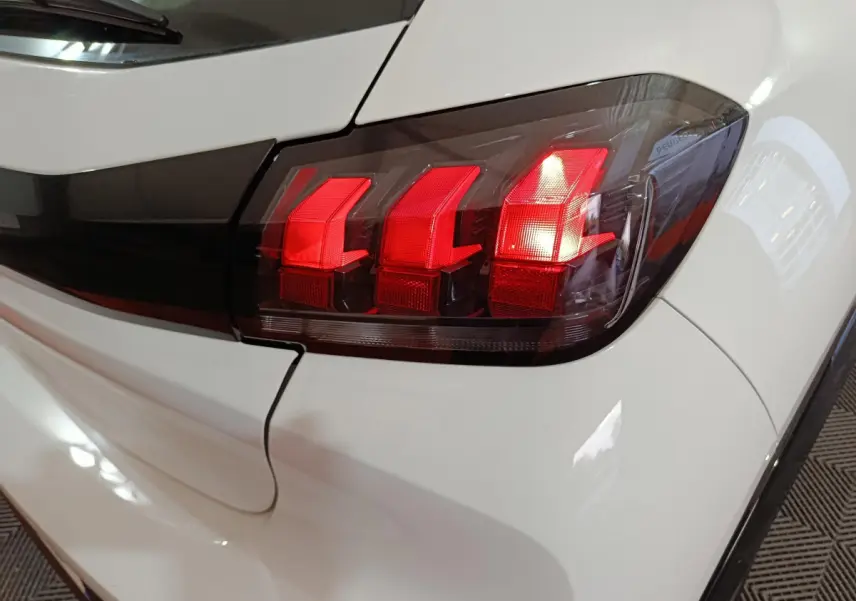Gros plan sur le feu arrière droit rouge d'une Peugeot 208 électrique blanche, version 2023 Active Pack.