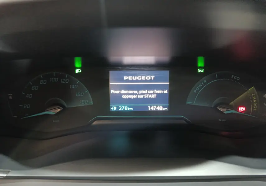 Tableau de bord numérique de Peugeot 208 électrique 2023, affichant l'autonomie et les voyants allumés.