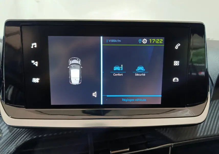 Écran tactile central de la Peugeot 208 électrique blanche affichant les réglages confort et sécurité.