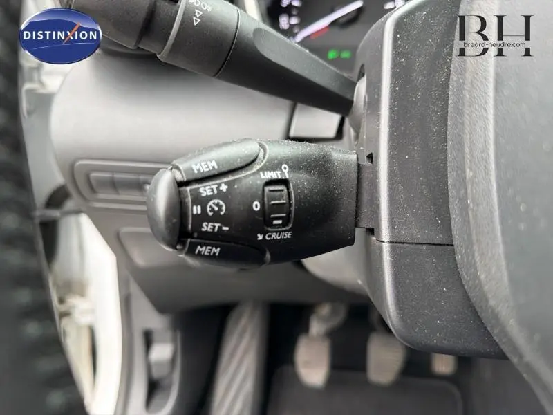 Gros plan sur la commande de régulateur de vitesse noire côté gauche du volant d'une Citroën C3 Aircross blanche.