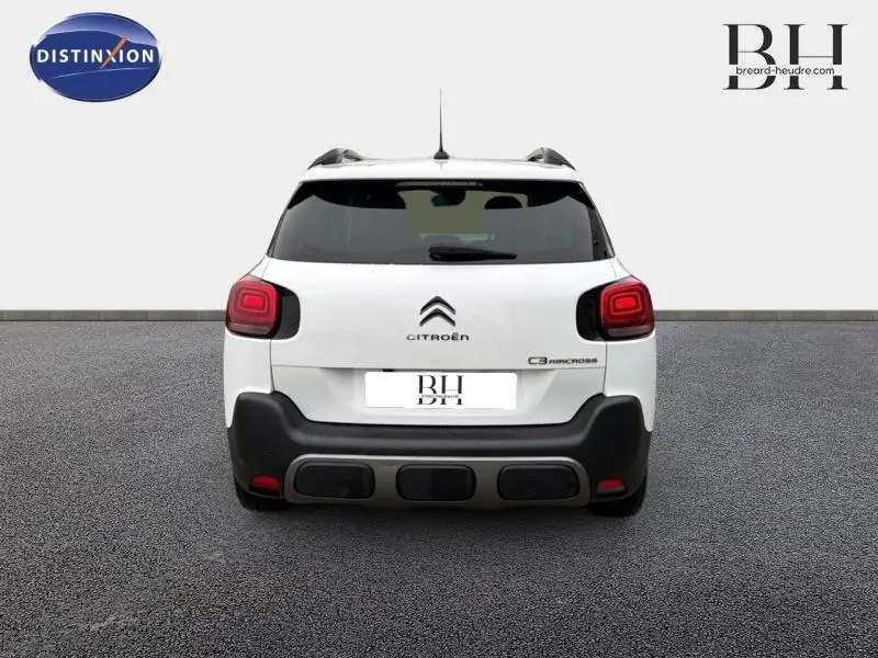 Vue arrière d'un Citroën C3 Aircross 2018 blanc Natural White avec barres de toit et feux arrière distinctifs rouges.