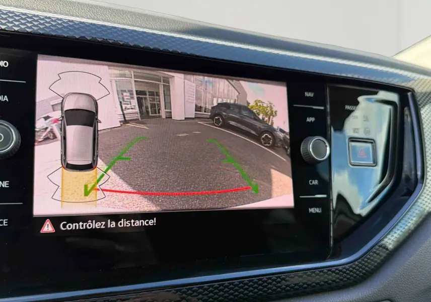Écran tactile intérieur montrant la caméra de recul active avec vue arrière et guidage de trajectoire verte et rouge.