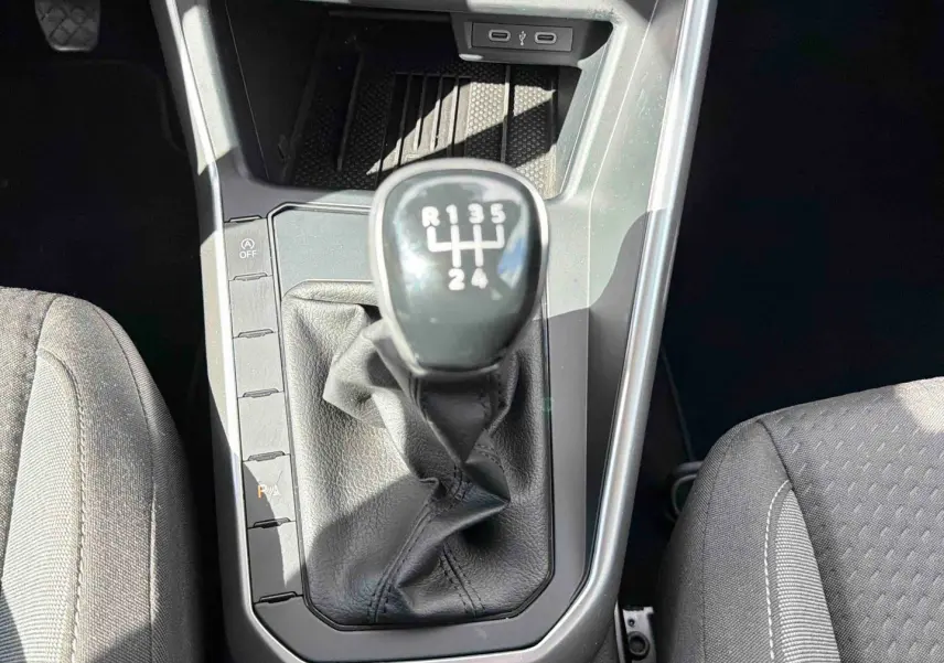 Vue plongeante sur la console centrale de la Volkswagen Polo blanche, mettant en valeur le levier de vitesse manuel noir.