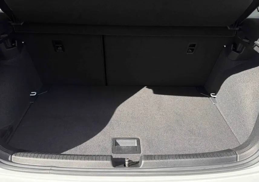 Coffre ouvert vu de face d'une Volkswagen Polo blanche, montrant un espace de chargement vide et propre.
