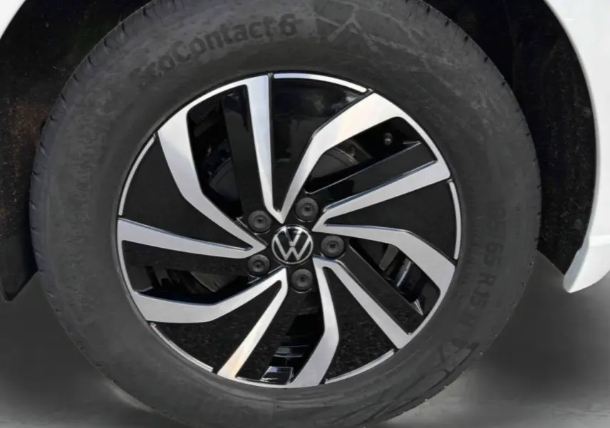 Gros plan sur la jante alliage 15 pouces bicolore noire et argentée d’une Volkswagen Polo blanche, pneu 185/65 R15 visible.