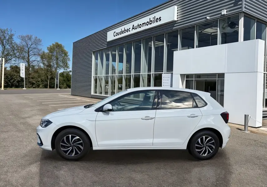 Vue de profil côté gauche d'une Volkswagen Polo blanche 2025 avec jantes alliage 15 pouces, stationnée devant un bâtiment.
