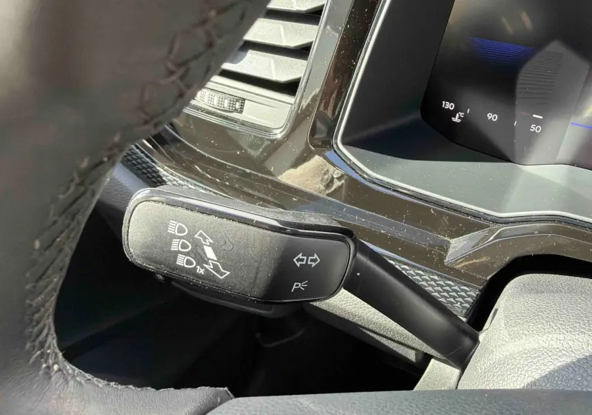 Gros plan sur la manette de clignotants à gauche du volant dans l’habitacle d’une Volkswagen Polo blanche.