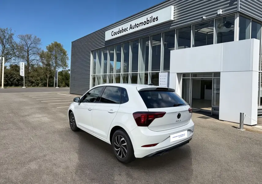 Vue 3/4 arrière droite d'une Volkswagen Polo blanche 2025 stationnée devant un concessionnaire Coudebec Automobiles.