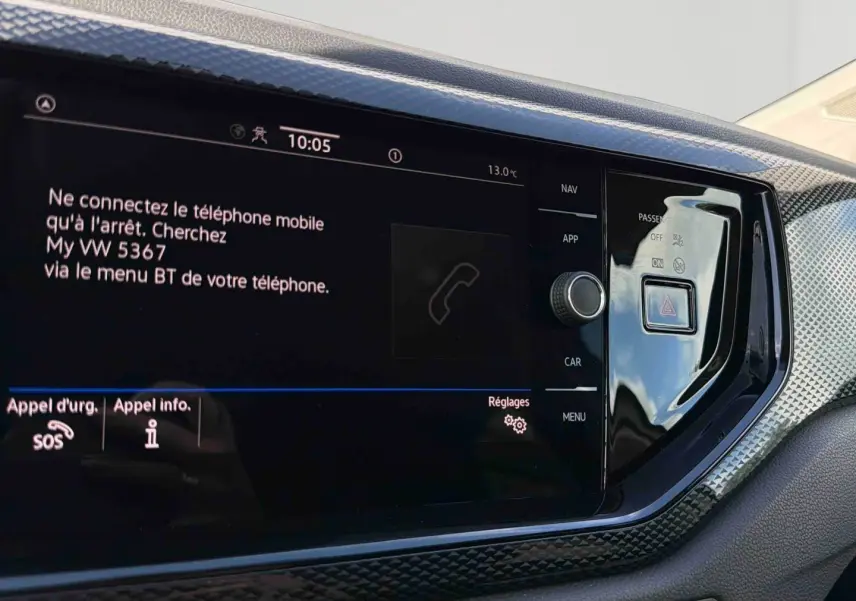 Vue rapprochée de l'écran tactile central et de la console noire brillante du tableau de bord de la Volkswagen Polo blanche.