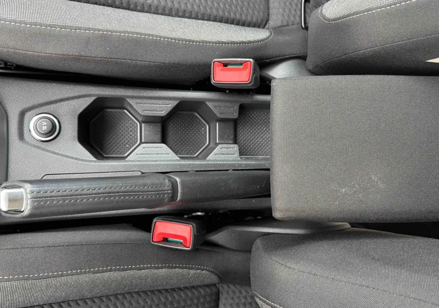 Vue plongeante sur la console centrale noire de la Volkswagen Polo 2025 avec frein à main et porte-gobelets.