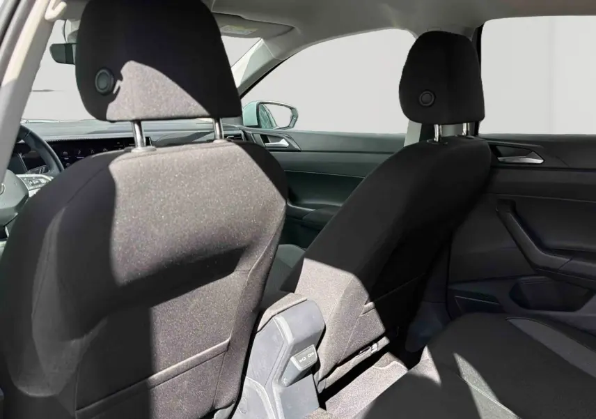 Vue intérieure arrière montrant les sièges avant noirs et la console centrale d'une Volkswagen Polo blanche 2025.
