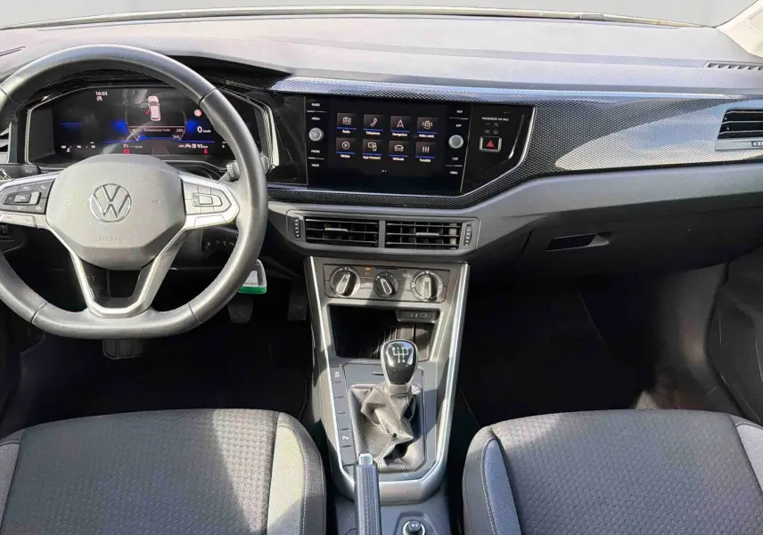 Vue intérieure avant de la Volkswagen Polo 2025, montrant le volant cuir, écran tactile et levier de vitesses manuel.