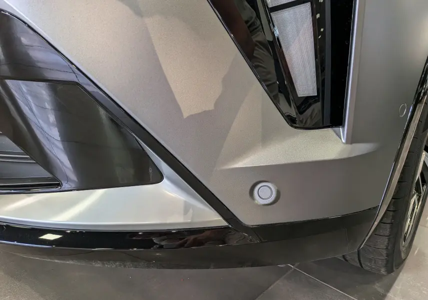 Gros plan sur l'angle avant droit gris schiste satin du Renault Rafale 2026, avec détails noirs brillants et capteur de stationnement.