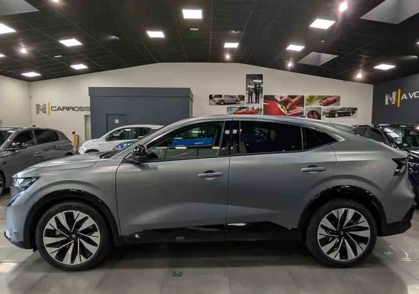 Vue de profil côté gauche du Renault Rafale gris schiste satin, soulignant ses jantes bi-ton et sa silhouette dynamique en intérieur showroom.