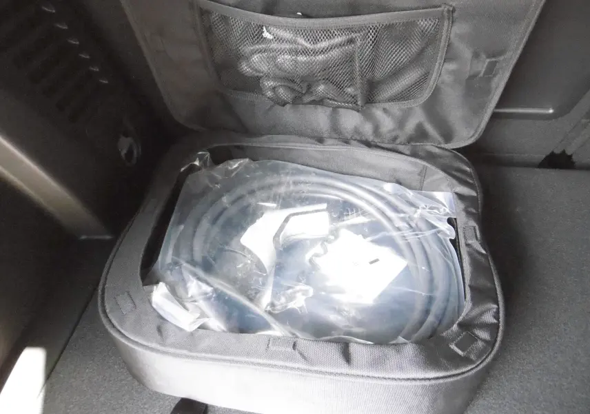 Chargeur de câble hybride dans le coffre d'un Peugeot 3008 gris Artense, vue rapprochée du rangement intérieur.