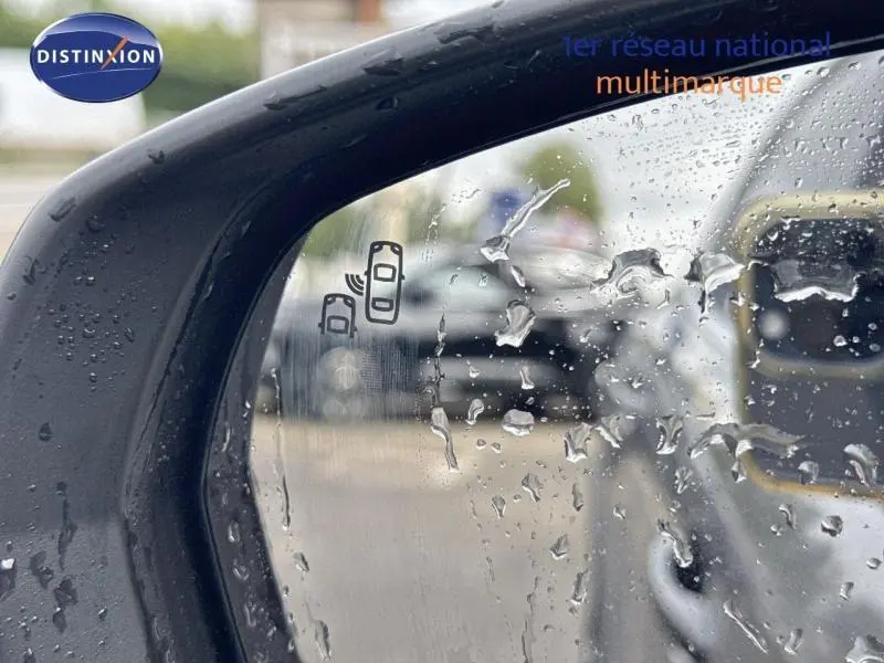 Gros plan sur le rétroviseur droit avec détection d'angle mort du Citroën C5 Aircross gris Platinium sous la pluie.