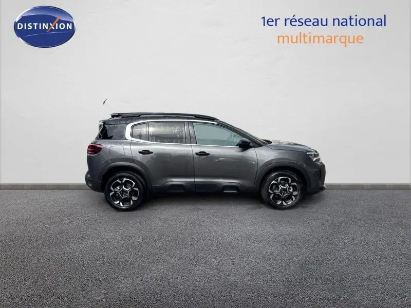 Profil droit d'un Citroën C5 Aircross 2025 gris Platinium avec barres de toit et jantes alu au design moderne.