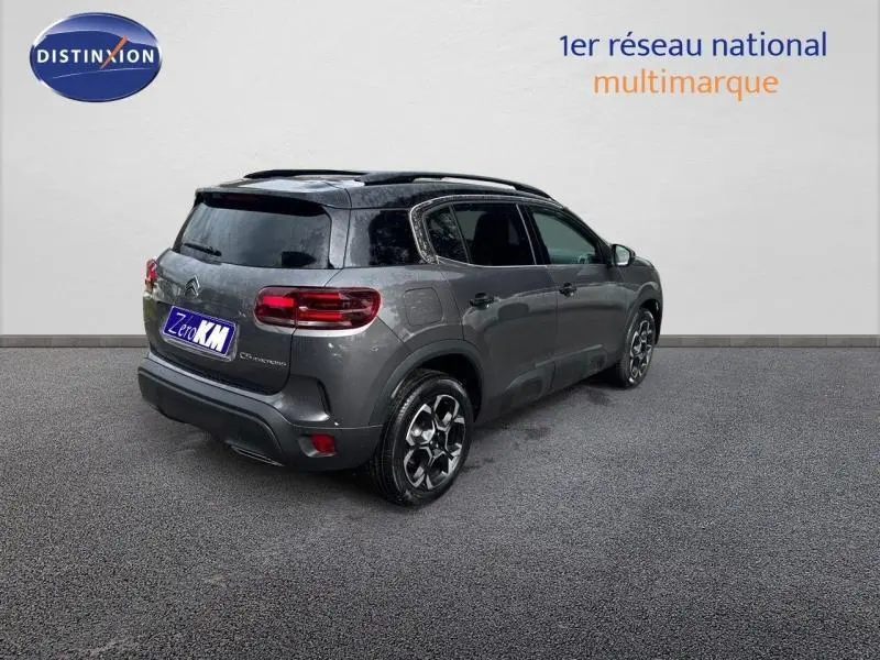 Citroën C5 Aircross gris Platinium vue 3/4 arrière droit avec barres de toit et vitres teintées.