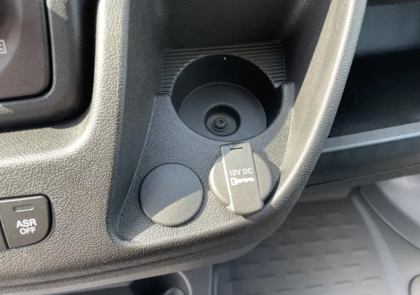 Prise 12V et porte-gobelets noirs en gros plan sur la console centrale du Peugeot Boxer Fourgon blanc 2023.