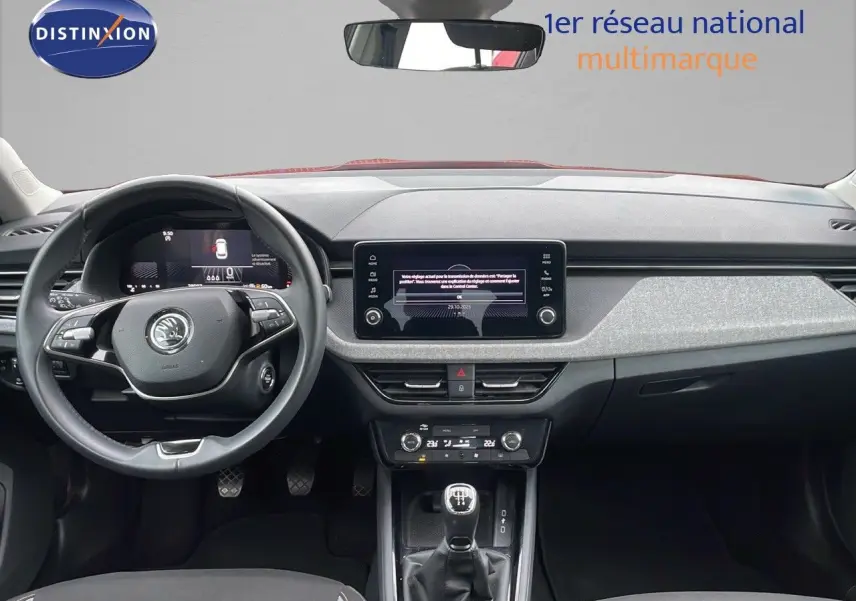 Vue frontale de l'habitacle du Skoda Kamiq rouge velvet metal 2024, avec tableau de bord moderne et boîte manuelle.