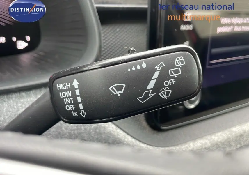 Gros plan sur la commande d'essuie-glace du Skoda Kamiq 2024 rouge velvet metal, avec affichage du tableau de bord en arrière-plan.