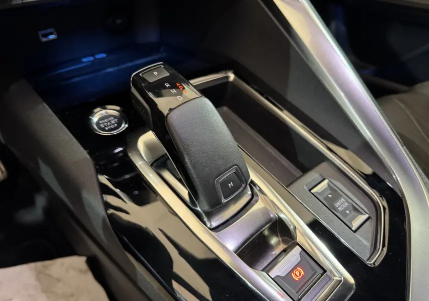 Gros plan sur la console centrale du Peugeot 3008 gris clair, montrant le levier de vitesse automatique et le bouton start/stop.